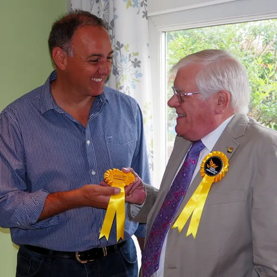 Cllr Ron Tindall (right) handing over a candidate rosette to Adrian England (left)